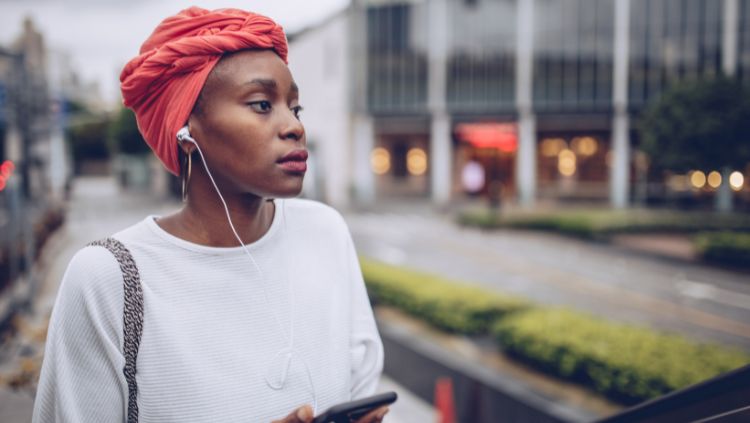 Woman will cellphone on city street symbolizing the importance of internet access for solo female travel safety