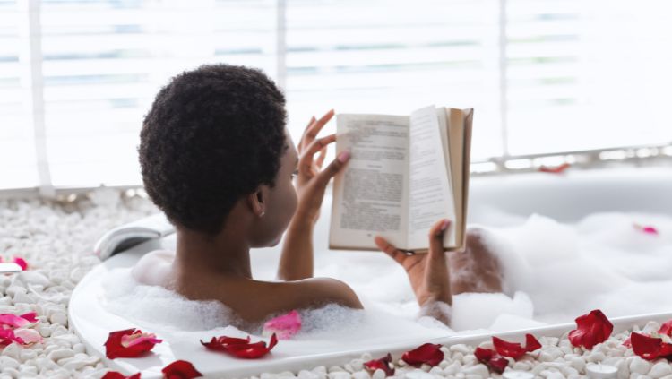 a woman indulges in solo travel for self-care, soaking in a tub with a book