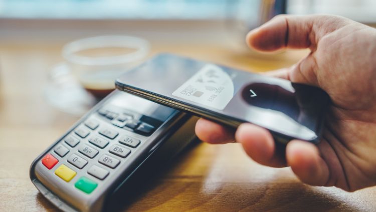 hand holding a smartphone next to a point of sale terminal