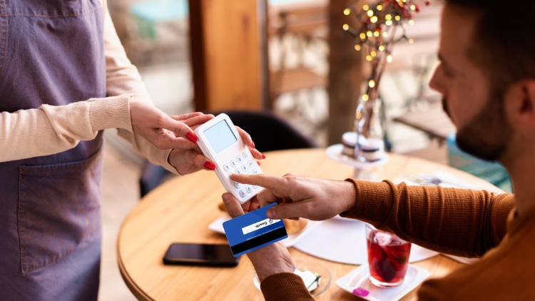 Man paying in restaurant. It makes a difference whether you choose your home or local currency