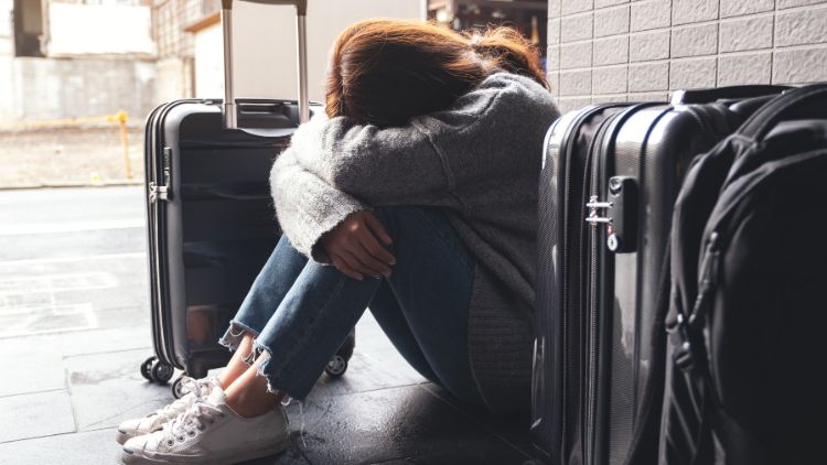 woman sitting on floor with suitcases experiencing travel anxiety