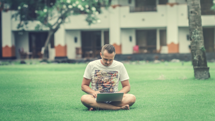 A man sitting in a park with a computer in his lap